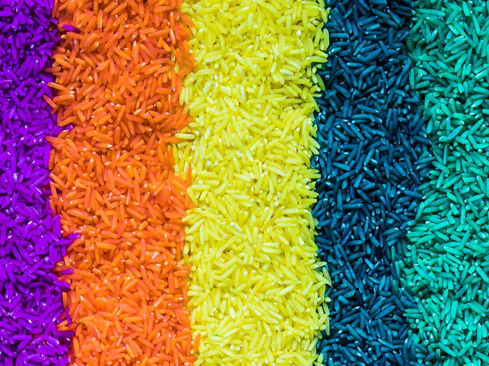 Colorful rainbow rice sensory bin with scoops and funnels for toddlers